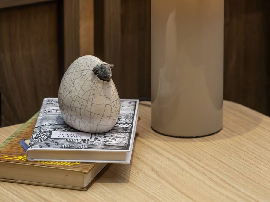Una mesa con una lámpara, un huevo decorativo y un libro titulado 'Stamford Bridge'.