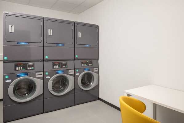 A laundry facility with four washing machines and a single dryer, arranged in two rows. - Residence Inn by Marriott Cork (Cork)