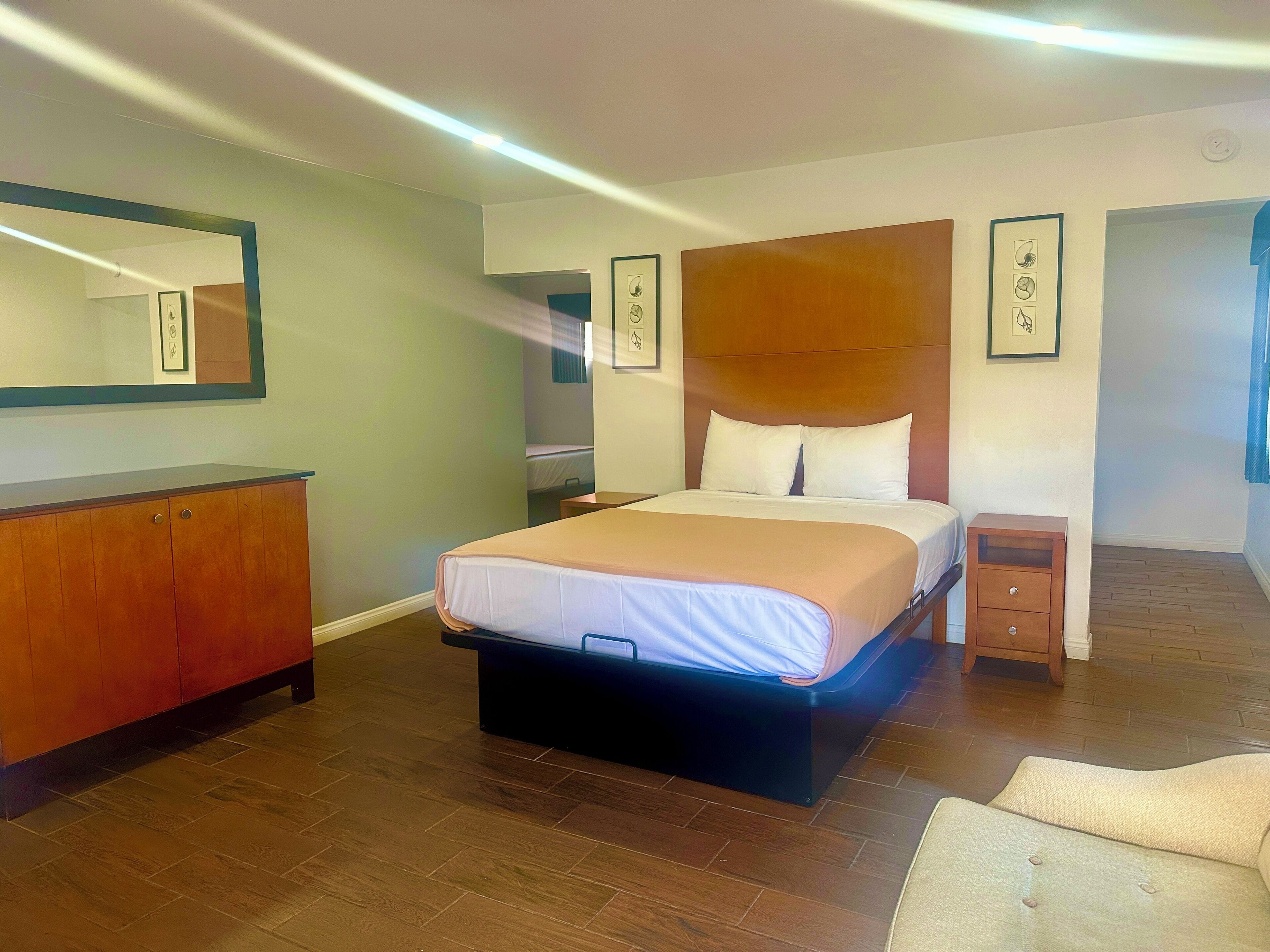Een hotelkamer met een bed, een houten dressoir, een nachtkastje en een stoel.