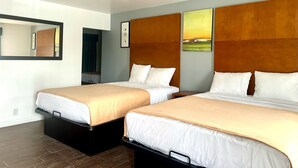 A hotel room with two beds, a large mirror, and artwork on the walls. - Oceanside Inn & Suites (Oceanside)