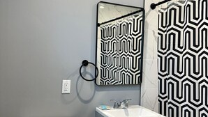A bathroom with a toilet, sink, and shower curtain. - Oceanside Inn & Suites (Oceanside)