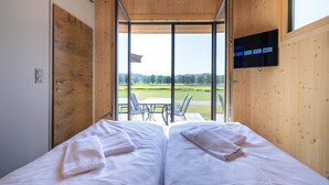 Un dormitorio con dos camas, un televisor montado en la pared y vistas al exterior.