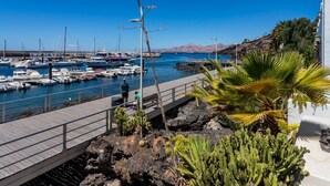 Un port de plaisance avec des bateaux amarrés, une promenade en bois et un terrain rocheux parsemé de cactus.