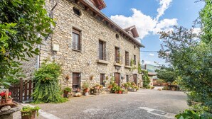 A stone building with multiple windows and balconies, surrounded by potted plants and a gravel courtyard. - Apartment 'Cambolino' with Mountain View, Private Terrace and Wi-Fi (Borrastre)