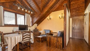 A cozy room with wooden furniture, a dining table, and a TV. - Apartment 'Cambolino' with Mountain View, Private Terrace and Wi-Fi (Borrastre)