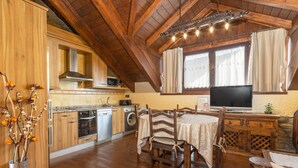 A rustic kitchen with wooden cabinets, a dining table, and a television. - Apartment 'Cambolino' with Mountain View, Private Terrace and Wi-Fi (Borrastre)