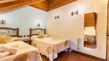 A room with two beds, wooden beams, a stone wall, and a mirror.