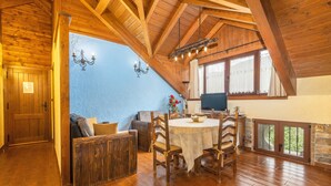 Un comedor con una mesa y sillas de madera, una araña y un televisor.