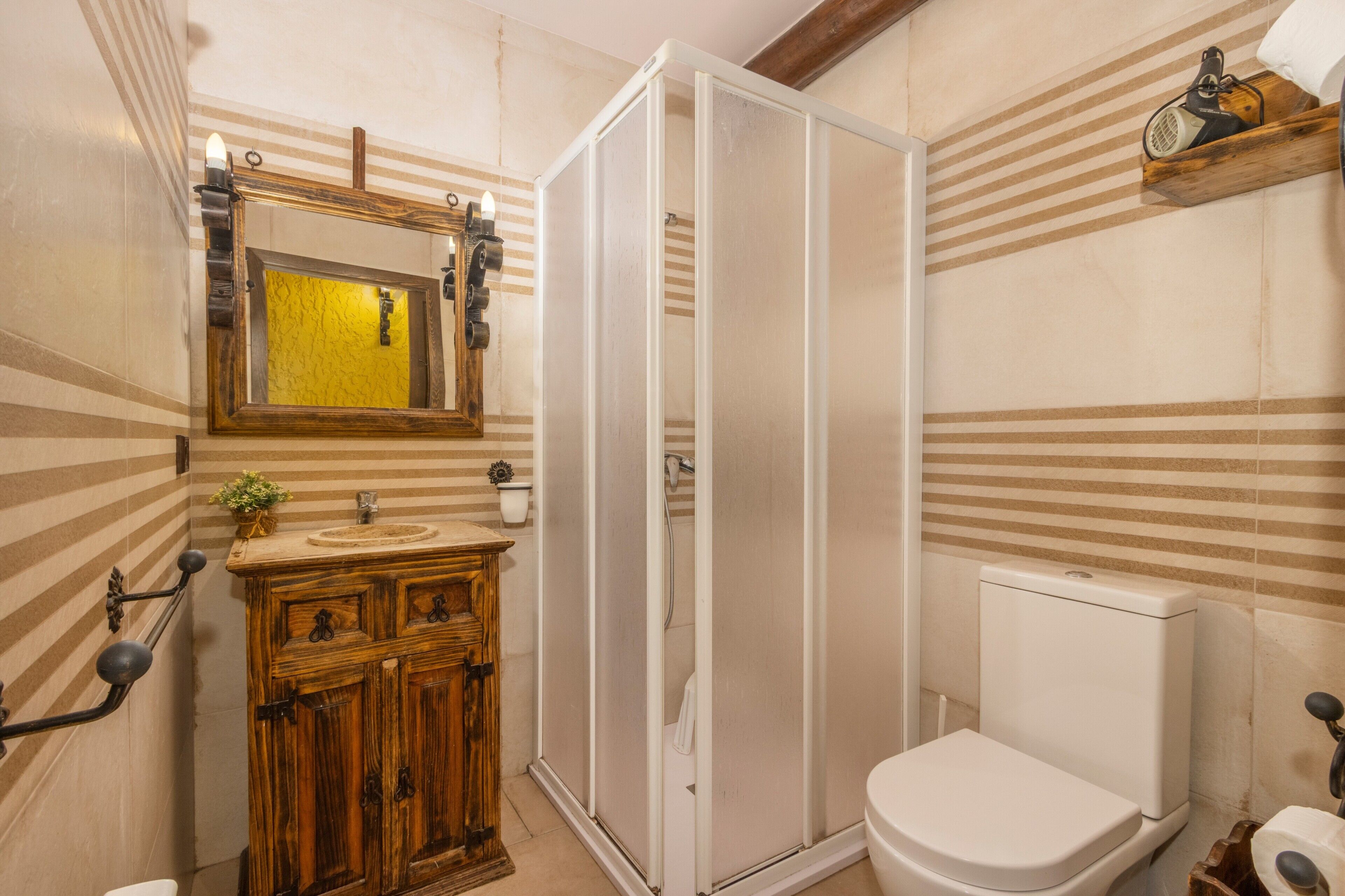 Ein Badezimmer mit einem Holzkosmetikschrank, einer weißen Toilette, einer Duschkabine und einer gestreiften Wandgestaltung.