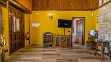 Un hall con suelo de madera, televisión, botellero y pared de piedra.