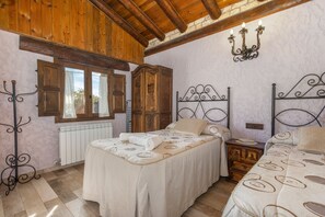 A bedroom with a wooden ceiling, a bed with a patterned bedspread, a nightstand, and a window with curtains. - Apartment 'Cabaña Vegara' with Mountain View, Private Terrace and Wi-Fi (Borrastre)