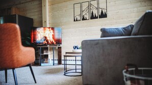 A cozy living room with a fireplace, a television, and a sofa. - Raven's Spruce Suite #7 Getaway (Fairbanks)