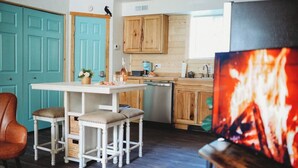 A compact kitchen with wooden cabinets, a white countertop, and a bar stool. - Raven's Spruce Suite #7 Getaway (Fairbanks)