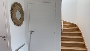 Une porte blanche avec un trou de serrure, un cadre de porte en bois et un escalier en bois muni d’une main courante.