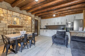 A rustic kitchen with stone walls, wooden beams, a dining table with chairs, and a sofa. - Apartment 'Galamín' with Mountain View, Private Terrace and Wi-Fi (Borrastre)