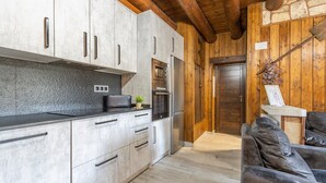 Eine Küche mit modernen Geräten, einer Steinwand, Holzbalken und einem Ledersofa.