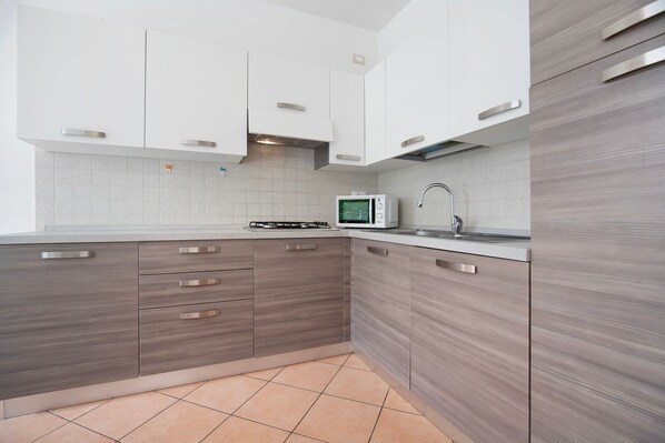 Una cocina moderna con armarios blancos, un microondas y una estufa a gas.