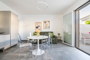 Un intérieur moderne comprenant un coin repas, un canapé et une porte-fenêtre coulissante donnant sur un espace extérieur.