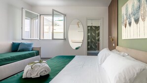 Ett hotellrum med en säng, en soffa, en spegel och utsikt över omgivningarna.