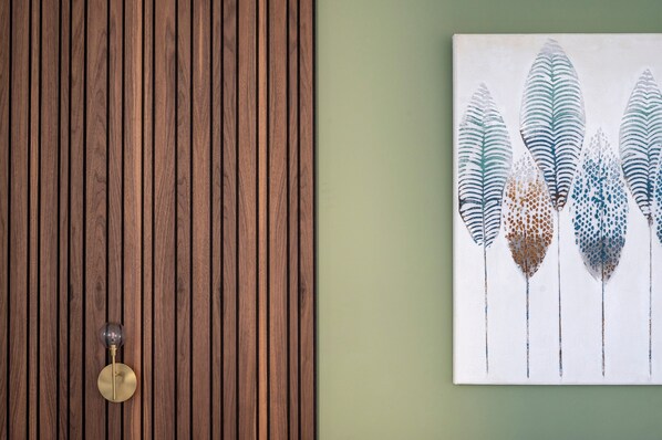 Pared de paneles de madera con un pomo de latón y una obra de arte montada en la pared con diseños estilizados de plumas.