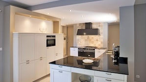 A modern kitchen with white cabinetry, a black countertop, and a patterned backsplash.