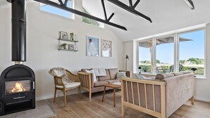 A cozy living room with a fireplace, wooden furniture, and large windows offering a view of the outdoors. - Awesome home in Bogense with WiFi (Bogense)