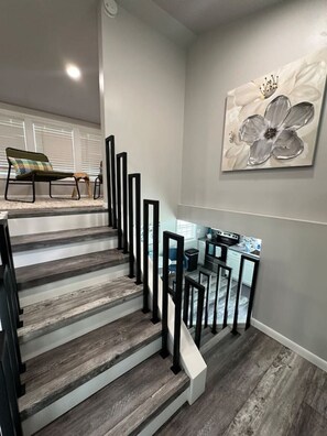 A staircase with wooden steps and black railings leading to a kitchen area.