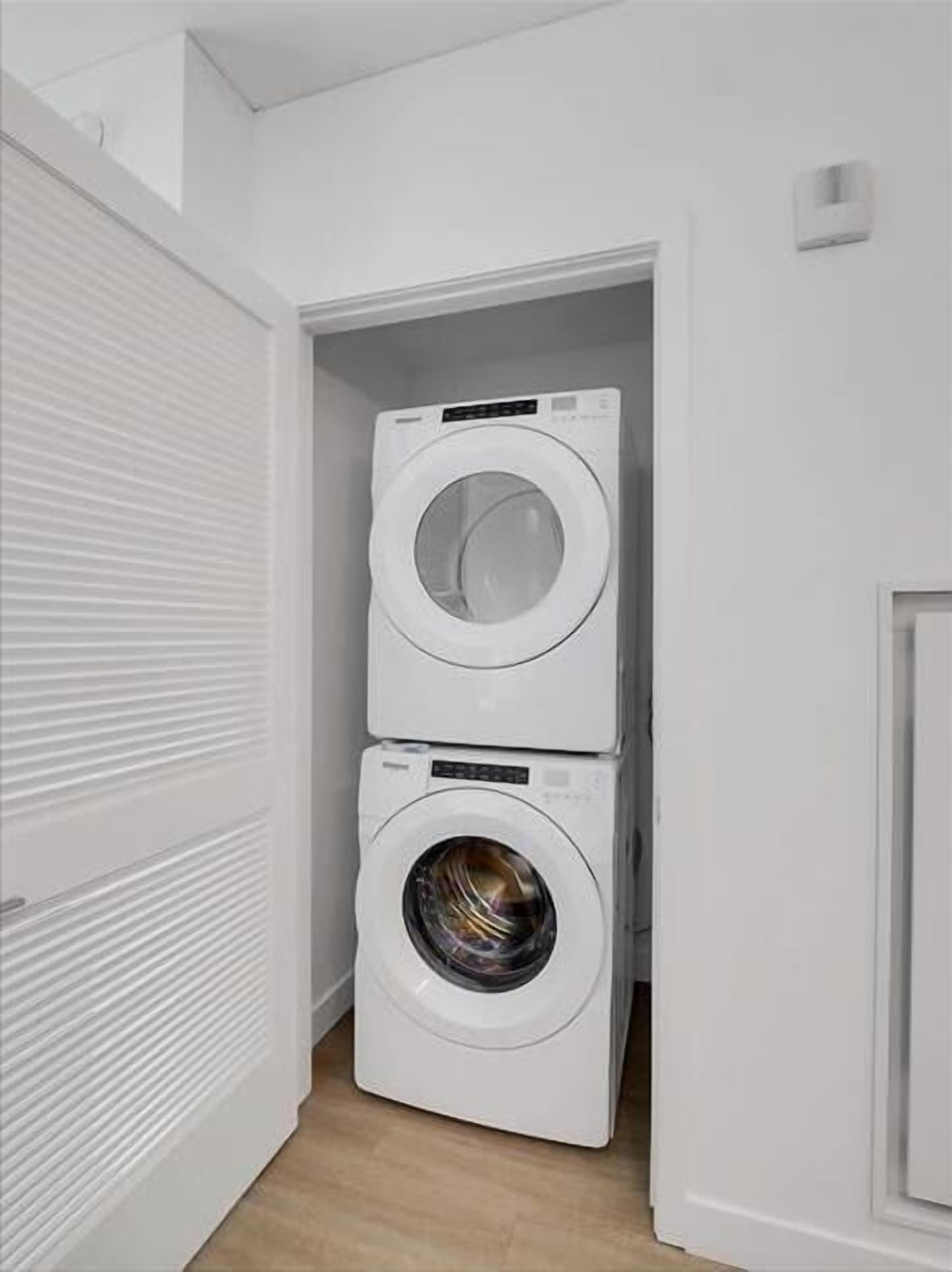 A laundry room with two stacked washing machines and a closed door.
