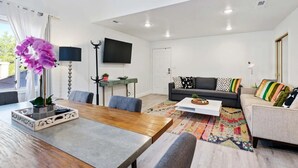 A modern living room with a sofa, a dining table, and a TV. - Cozy 2-bedroom 2nd story condo with AC, fitness room and WiFi in St. George Utah (St. George)