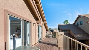 A balcony with a glass table and chairs, a sliding glass door leading to a bedroom, and a view of neighboring buildings. - Cozy 2-bedroom 2nd story condo with AC, fitness room and WiFi in St. George Utah (St. George)