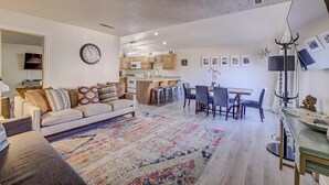 A modern living room with a sofa, coffee table, and a colorful rug. There is a dining area with a table and chairs, and a kitchen in the background. - Cozy 2-bedroom 2nd story condo with AC, fitness room and WiFi in St. George Utah (St. George)