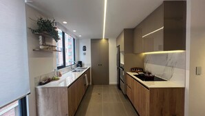 A modern kitchen with wooden cabinets, a central island, and a built-in oven. - Luxurious and comfortable suite close to La Carolina Park (Quito)