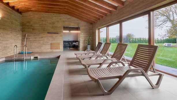 Una piscina amb gandules, bigues de fusta al sostre i grans finestres.