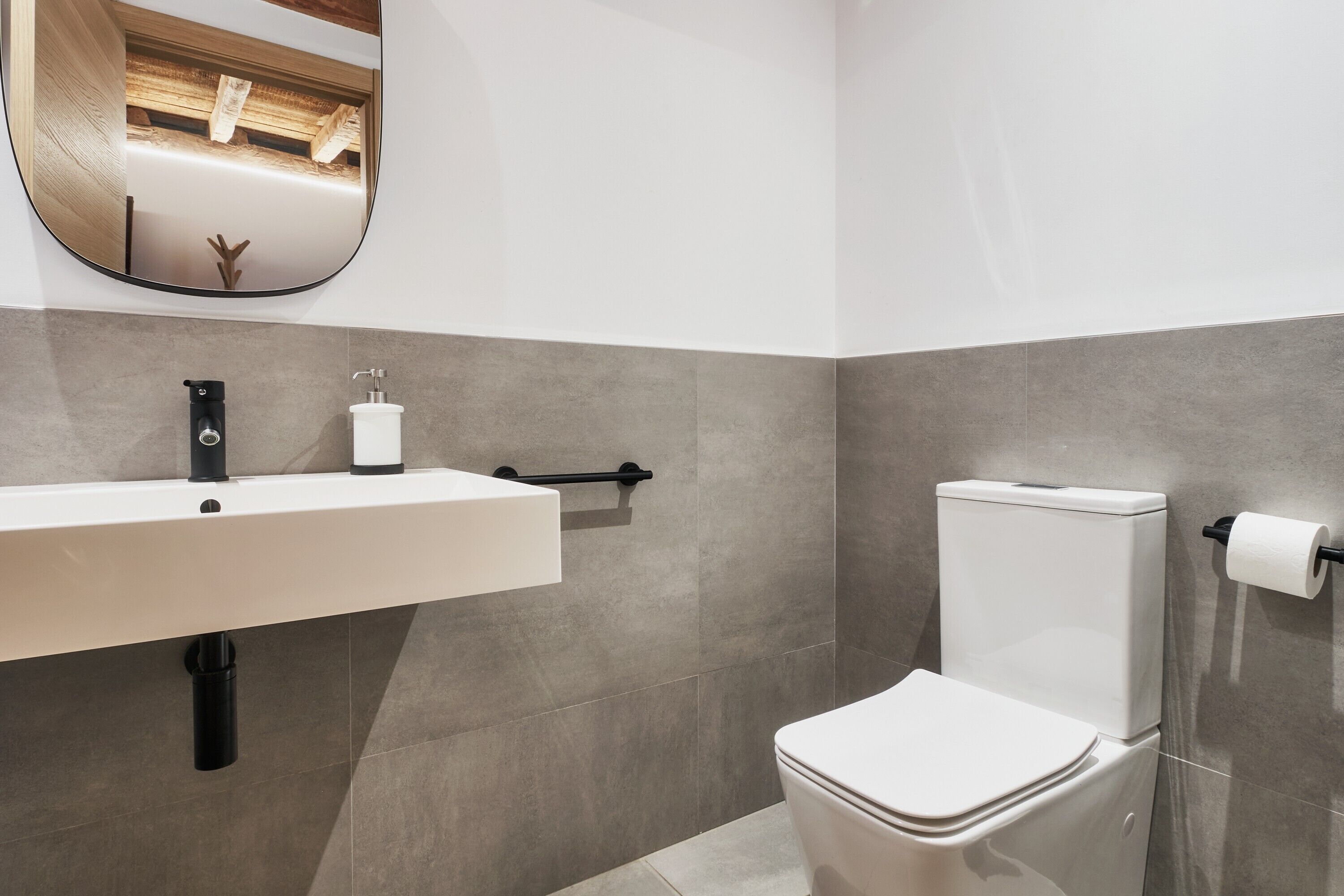 Une salle de bain moderne avec un lavabo blanc, un robinet noir et des toilettes.