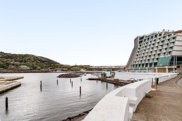Een hotel aan het water met een modern design, met een jachthaven en een heuvelachtig landschap op de achtergrond.