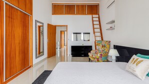 Une chambre à coucher avec un lit, une commode, une chaise, un téléviseur, une cheminée et une échelle.