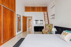 Quarto com cama, cômoda, cadeira, televisão, lareira e escada.
