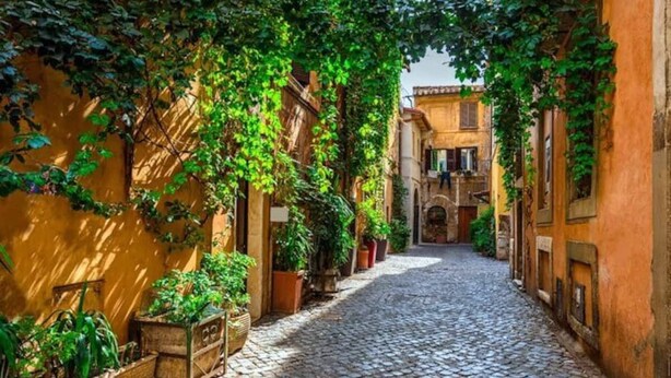 Une rue pavée bordée d’immeubles recouverts de verdure, ce qui évoque un cadre historique ou pittoresque.