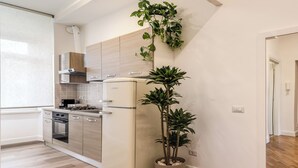 Une cuisine moderne équipée d’un réfrigérateur, d’un four et d’un évier, ainsi que d’une plante en pot.