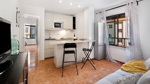 A compact living space with a kitchenette, a sofa, and a TV.