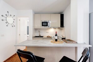 A modern kitchen with a microwave, wine bottle, and glasses on the counter.
