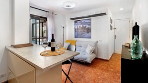A modern kitchen with a dining area, a sofa, and a large window.