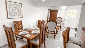 A dining area with a wooden table and chairs, a chandelier, and a framed artwork on the wall. - Senderos del botánico  (Santiago de los Caballeros)