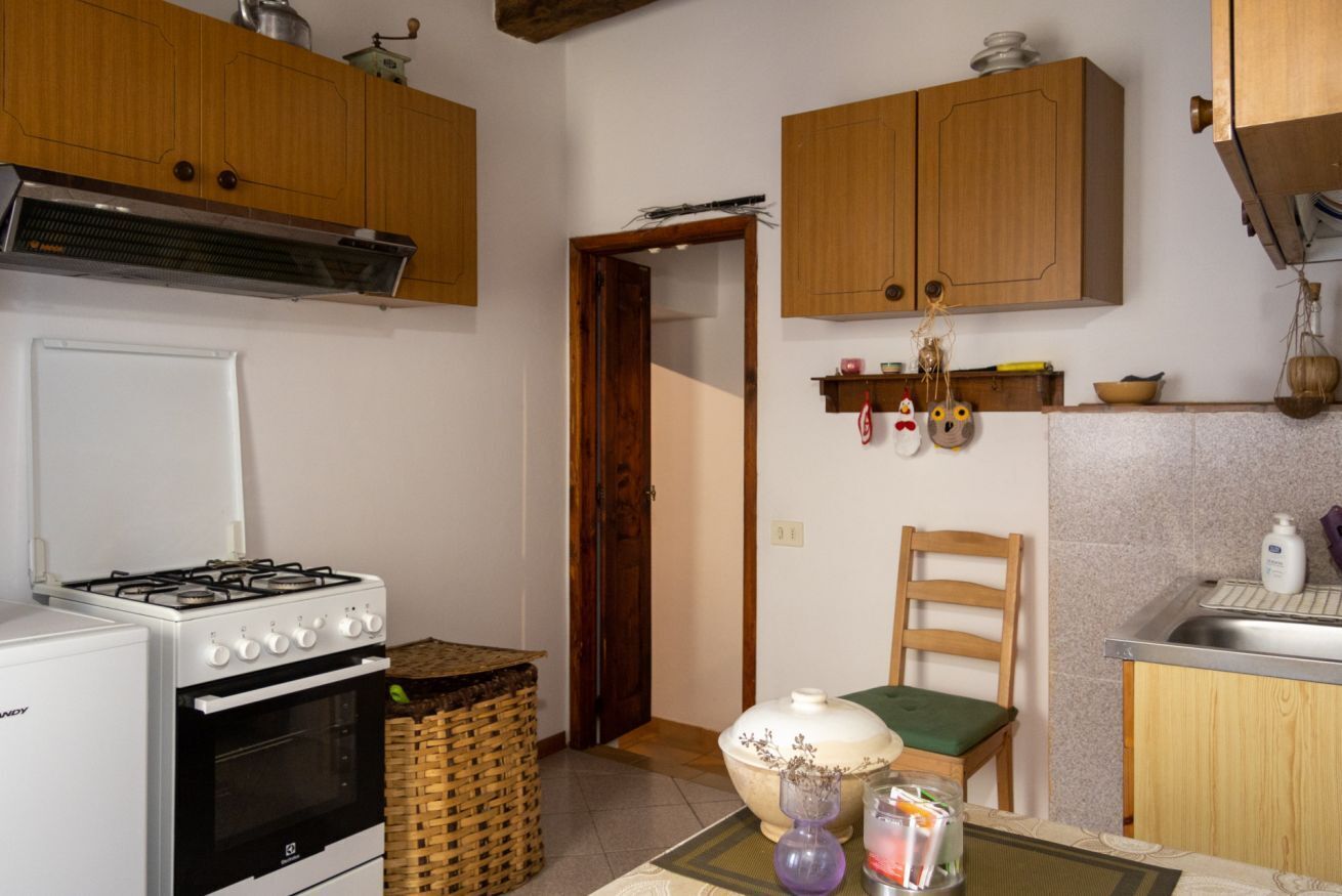 Une cuisine avec des armoires en bois, une cuisinière, un évier et une chaise.