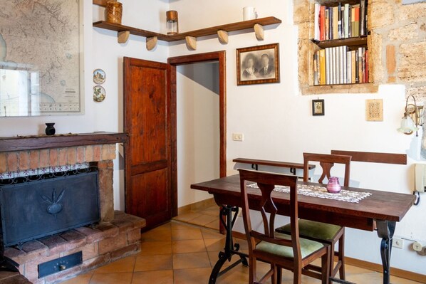 Un coin repas avec une table en bois, des chaises, une cheminée, une bibliothèque et une carte accrochée au mur.