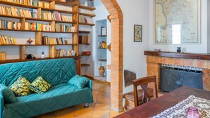 A cozy room with a teal sofa, wooden bookshelves, a fireplace, and a map on the wall.