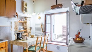 A kitchen with wooden cabinets, a dining table with chairs, a coffee maker, and a window with a view.