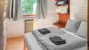 A bedroom with a bed, a radiator, a window with curtains, and a shelf with folded blankets. - 2 bedroom awesome home in Ferlach (Ferlach)