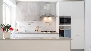 Une cuisine moderne avec des meubles blancs, une hotte en acier inoxydable, un four à micro-ondes et un four traditionnel.