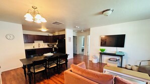 A modern living room with a sofa, a dining table with chairs, a kitchen area with dark wooden cabinets, a microwave, and a refrigerator. - NEW LISTING- Brookwillow Retreat (Grand Junction)